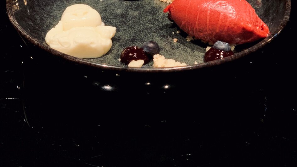 Kreatives Dessert in einer schwarzen Schale mit Sorbet und Beeren.