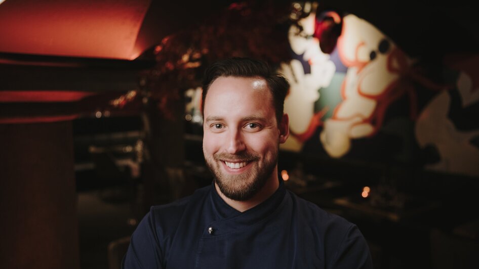 Ein lächelnder Koch in einem Restaurant mit modernem Design.