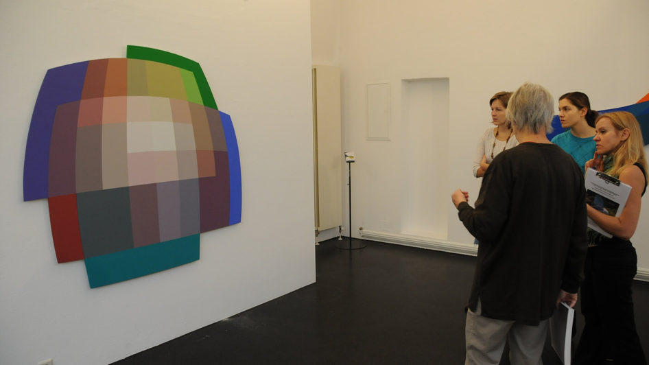 Besucher betrachten ein geometrisches Farbbild im Museum. | © MUWA