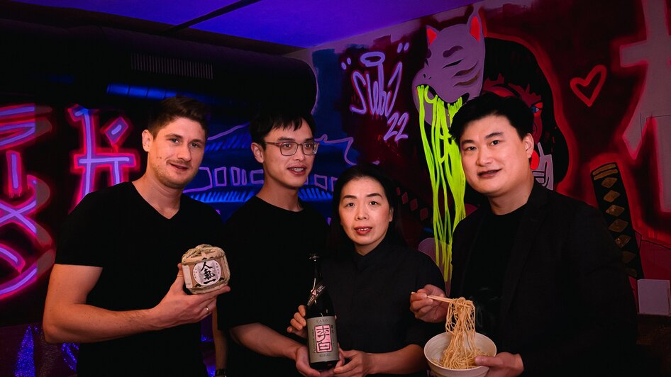 Vier Personen halten Nahrungsmittel und Getränke in einer stylischen Bar. | © Moriwano Group - jack-coleman.com