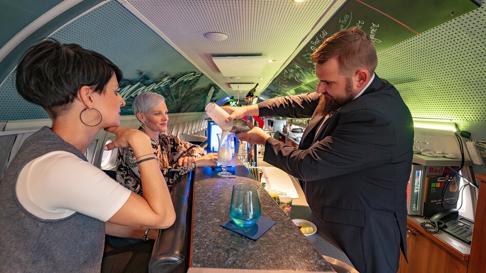 NOVA-AIR in Graz: Barkeeper mixt Drink für Gäste in stylisierter Atmosphäre. | © 5komma5sinne - Rene Strasser Fotografie