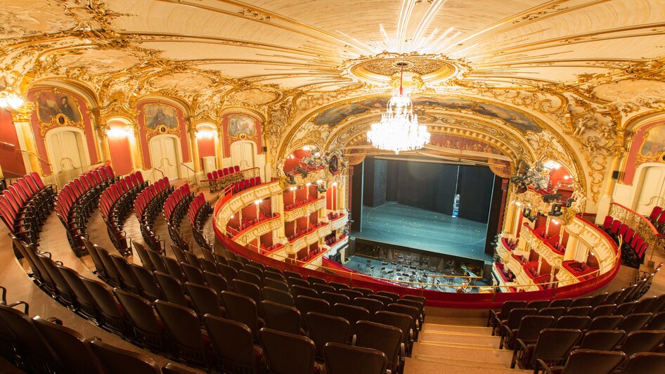Blick auf das prachtvolle Innere der Oper Graz, Stühle und Bühne sichtbar.
