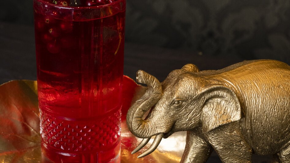 Ein goldener Elefant neben einem Glas mit rotem Getränk und Beeren. | © Jauk Katharina