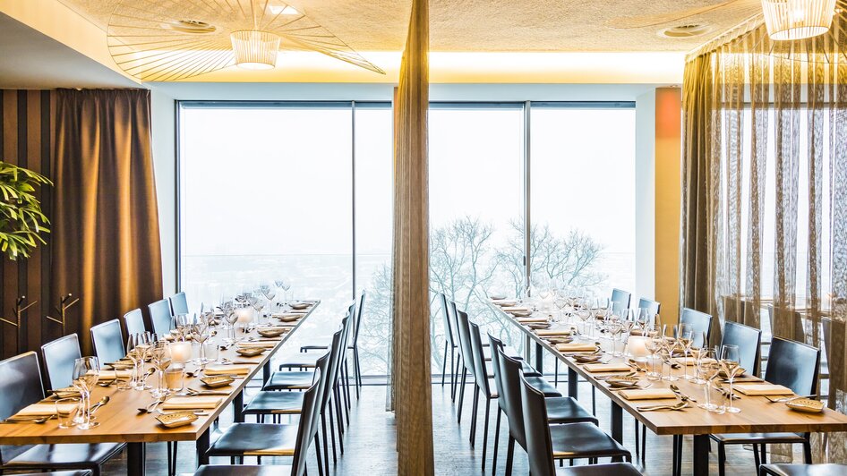 Moderne Restaurantansicht mit Tischdekoration und Panoramafenstern.