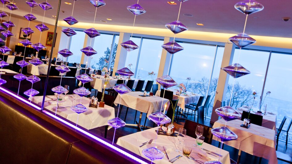 Moderne Restaurantansicht mit Tischdekoration und Glasobjekten.