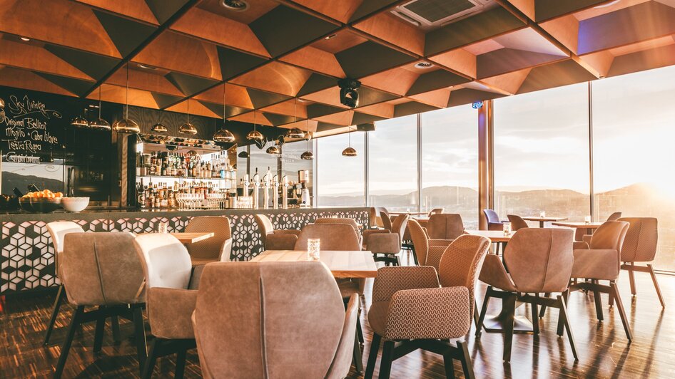 Moderne Architektur mit Holzdecke, beleuchtetem Barbereich und gemütlichen Sitzbereichen. Ideal für Tagungen und Business-Events.
