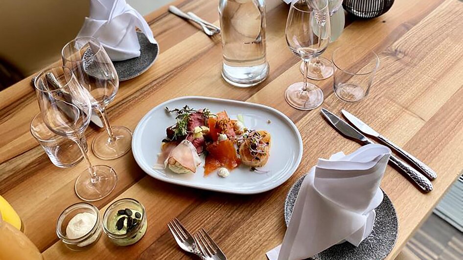 Im Schlossberg Restaurant sind ein elegant gedeckter Tisch und ein ansprechendes Essen mit Blick auf Graz zu sehen. Die moderne Atmosphäre und das stilvolle Ambiente bieten optimale Bedingungen für Business-Events und Tagungen.