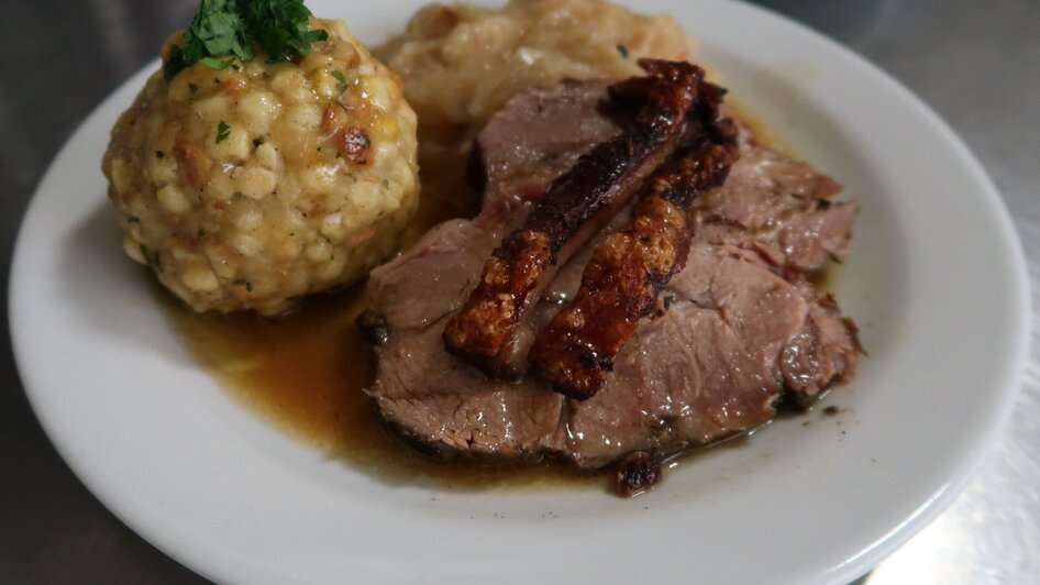 Ein Teller mit Schweinsbraten, Knödel und Sauerkraut.