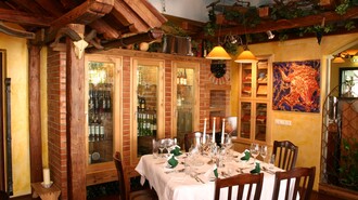 Helles Restaurant mit einem eleganten Tisch, Weinregalen und rustikalen Holzelementen. | © Rudolf