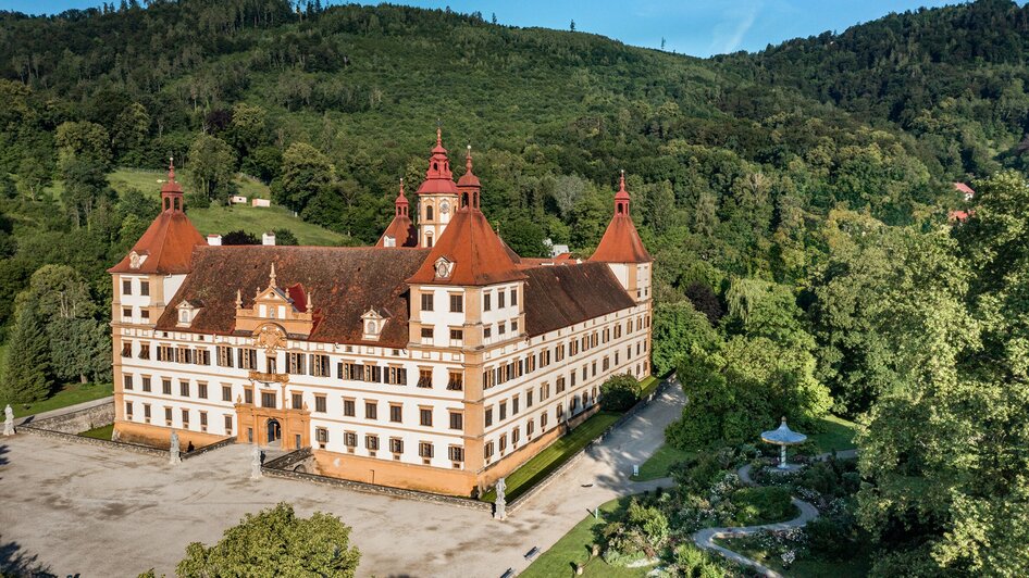 Luftbild des Schlosses Eggenberg in Graz, umgeben von grüner Landschaft.