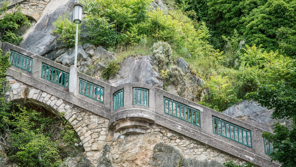 Zwei Personen auf dem Schlossbergsteig in Graz umgeben von Grün.