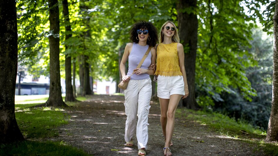 Zwei Frauen spazieren durch den Stadtpark in Graz.