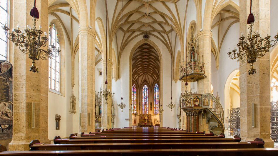 Innenansicht der Stadtpfarrkirche in Graz mit Kirchenbänken.