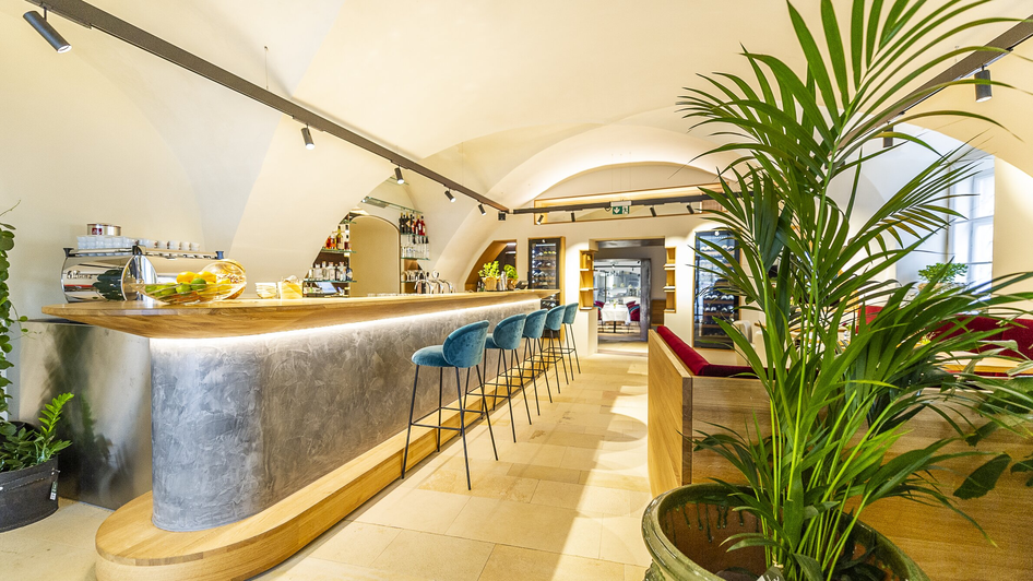 Moderne Bar mit Holztheke und Pflanzen, ideal für Snacks und Drinks. | © Paul Stajan