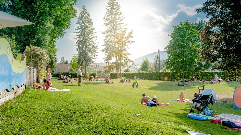 Besucher genießen einen sonnigen Tag im Stukitzbad in Graz auf der Wiese. | © Holding Graz - Joel Kernasenko