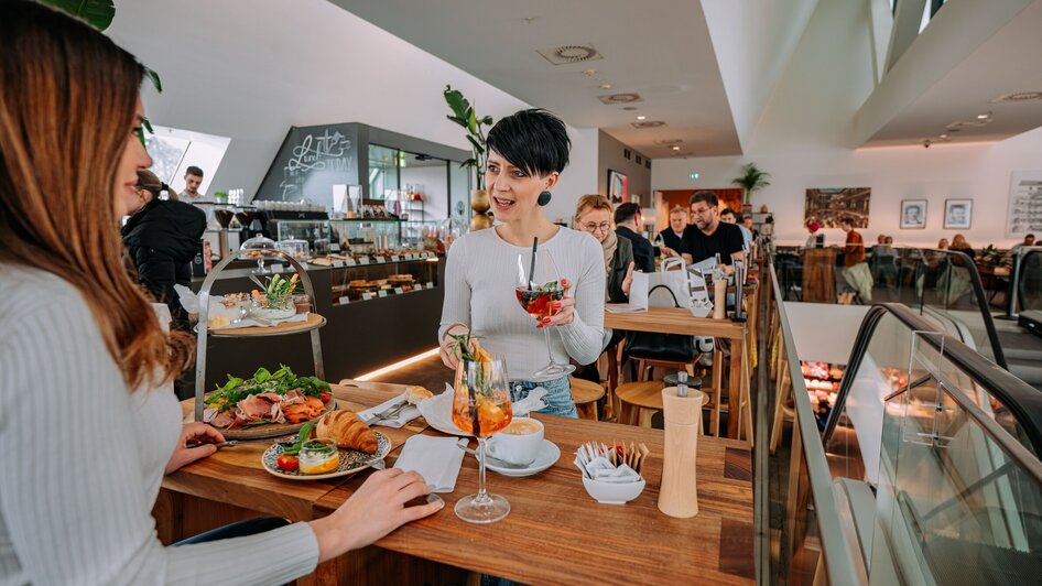 Zwei Frauen im Tagescafé Freiblick in Graz genießen Getränke und Essen.
