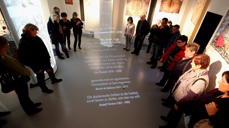 Besucher im Museum hören Zitate über Wissenschaft und Freiheit projiziert auf den Boden.