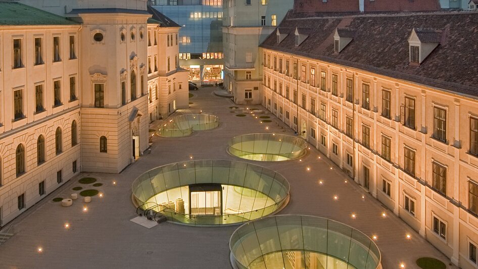 Der Innenhof eines modernen Gebäudes in Graz, umgeben von klassischer Architektur.