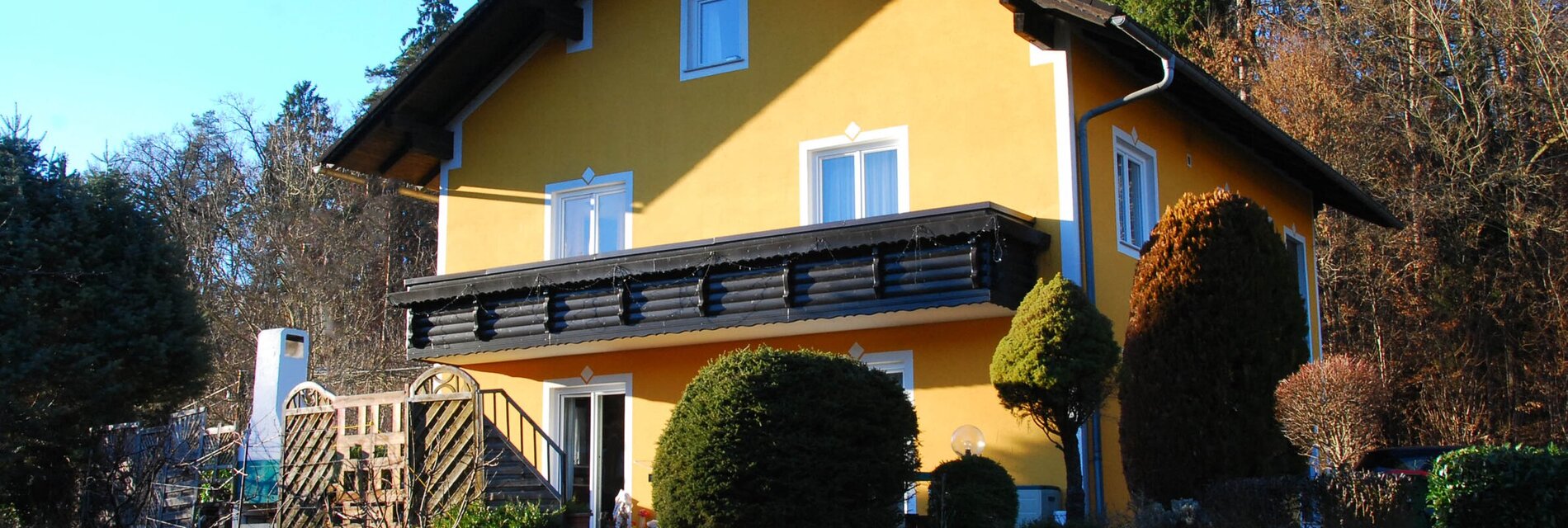 Gelbes Haus mit Balkon und Garten in ländlicher Umgebung.